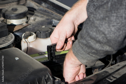 hands under the hood of a car, repair, battery replacement. auto repair shop, a man repairs a car under the hood of a car. close-up. Repair, maintenance, diagnostics concept