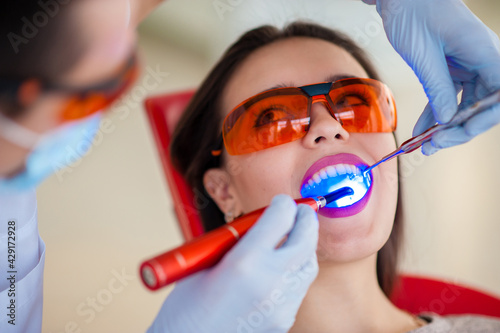dentist curing the patient's teeth with ultraviolet lamp in his office