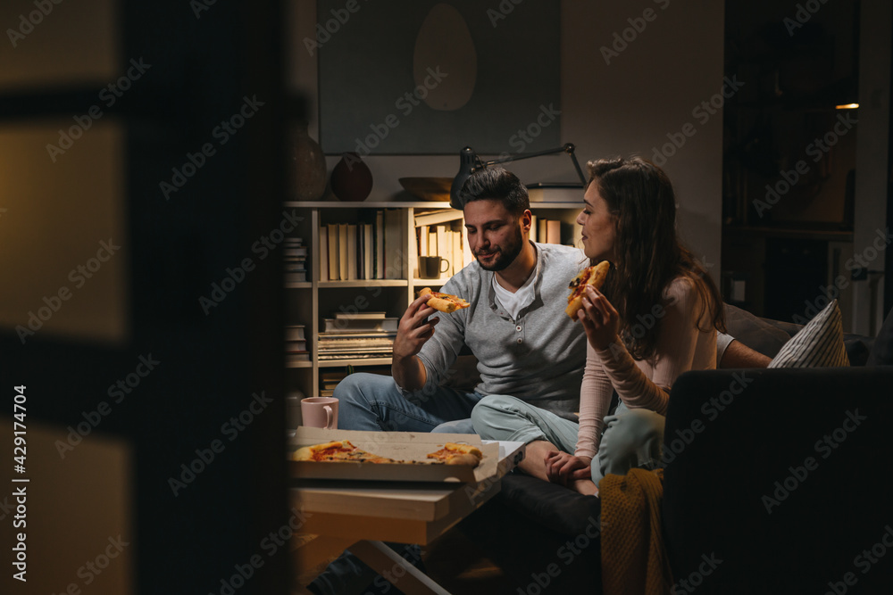 couple eating pizza at home. evening scene couple eating pizza at home. evening scene