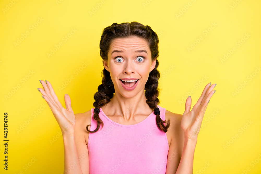 Photo of shiny shocked young lady braids dressed singlet rising arms big eyes isolated yellow color background Photo of shiny shocked young lady braids dressed singlet rising arms big eyes isolated yellow color background