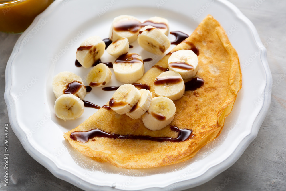 Close up of crepes with banana on white plate
