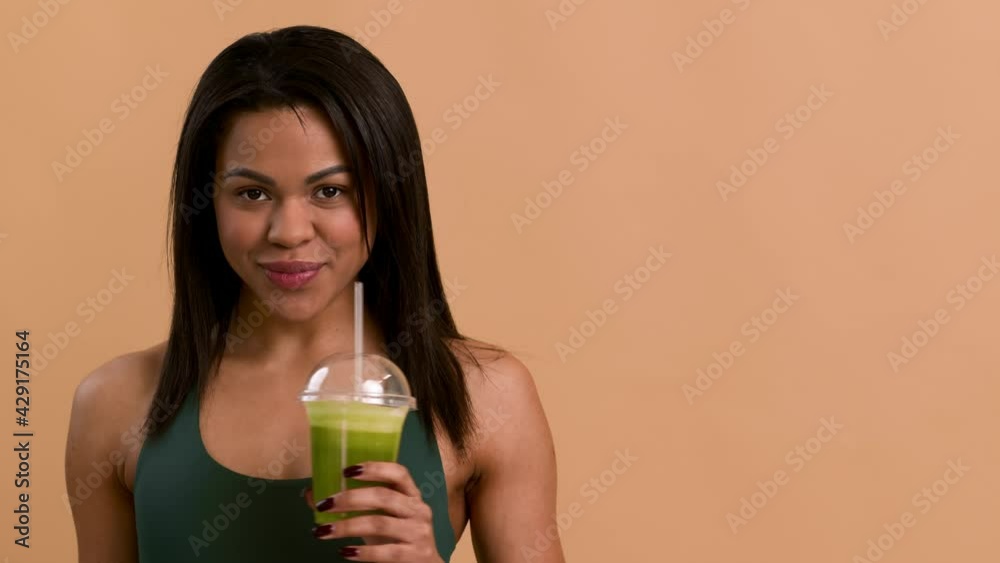 African Woman Drinking Smoothie Smiling To Camera Over Beige Background African Woman Drinking Smoothie Smiling To Camera Over Beige Background