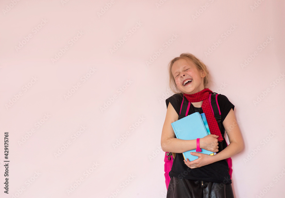 Portrait of a cheerful schoolgirl with a backpack and stationery on a light background. Space for the text. Back to school. Preparing for school. Selective focus Portrait of a cheerful schoolgirl with a backpack and stationery on a light background. Space for the text. Back to school. Preparing for school. Selective focus