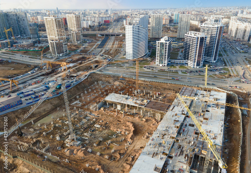 Drone view of a large construction site. Tower cranes in action on fog background. Housing renovation concept. Crane during formworks. Construction the buildings and multi-storey residential homes