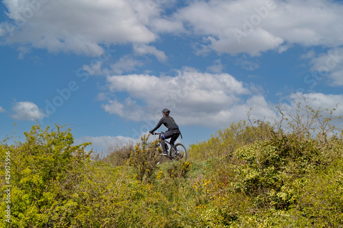 A woman cycling alone in the countryside with a blue sky background