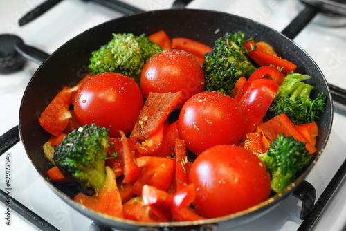Cooking vegetable stew in a pan. Tomatoes, bell peppers, broccoli. Grilled vegetables, vegan food. Selective focus