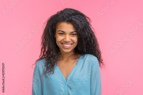 Close up portrait of young attractive dark skinned woman isolated over pastel pink background
