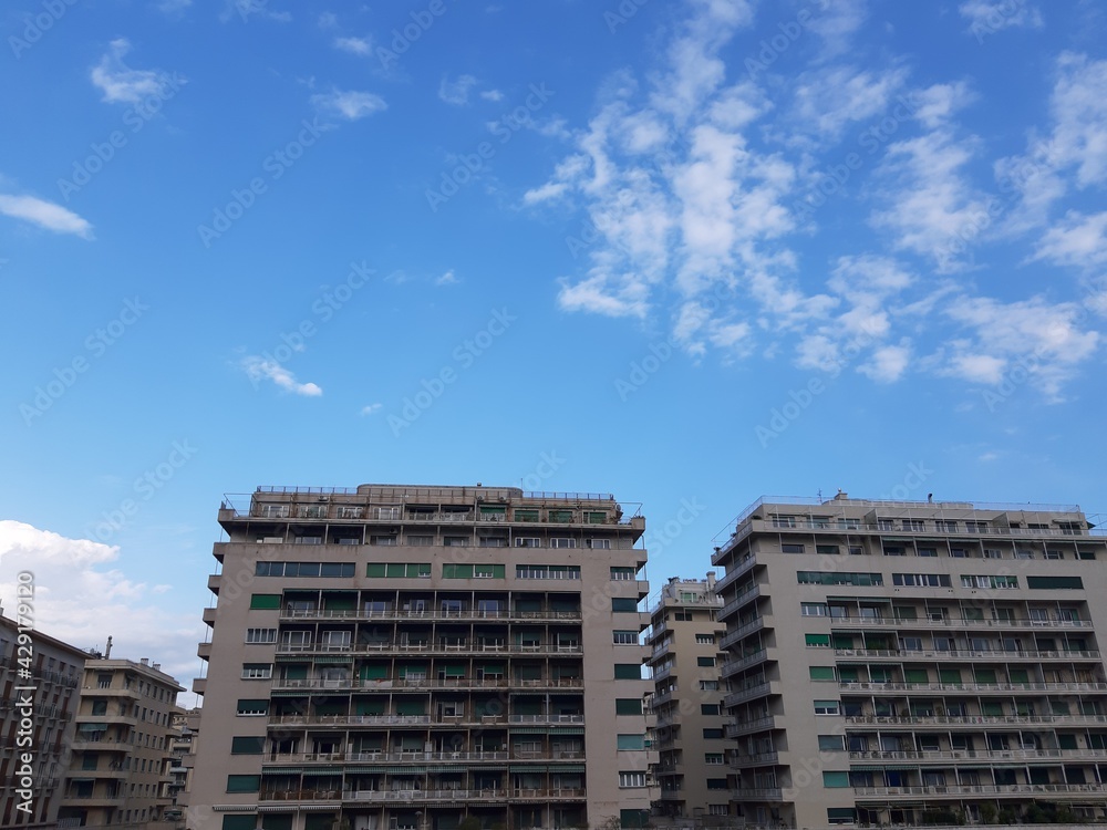 Fototapeta premium Genova, Italy - April 15, 2021: Modern construction in the city center of Genova, beautiful high skylines with grey and blue sky in the background in spring.