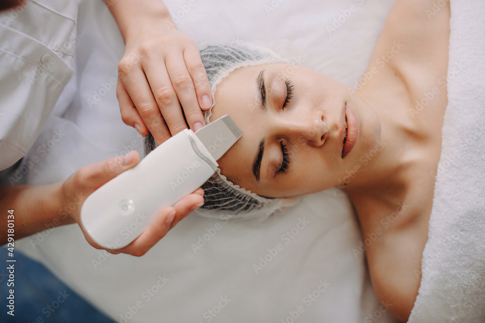 Fototapeta premium Top view photo of a caucasian woman lying while having professional spa procedures with apparatus at the salon