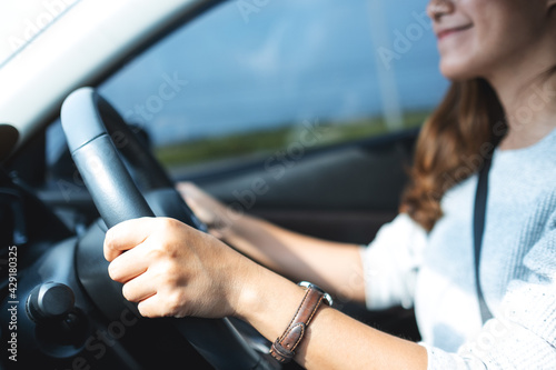 Closeup image of a beautiful young asian woman holding steering wheel while driving a car