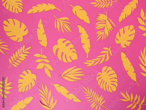 Natural tropical pattern with yellow paper palm leaves on pastel pink background. Minimal summer exotic texture concept. Flat lay, top view.