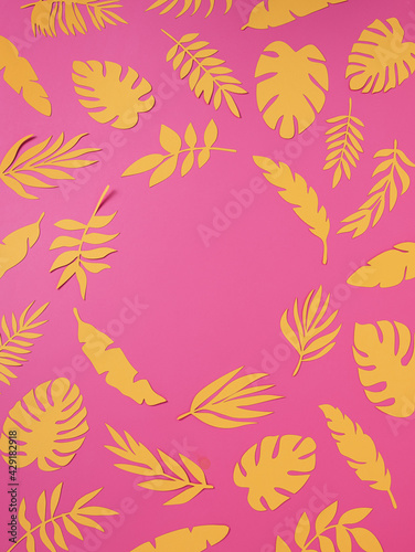 Natural tropical frame with yellow paper palm leaves on pink background. Minimal summer exotic texture concept with copy space for text. Flat lay, top view.