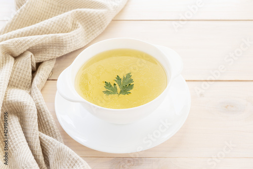 Homemade chicken bone broth with parsley in a white bowl. Healthly food. photo