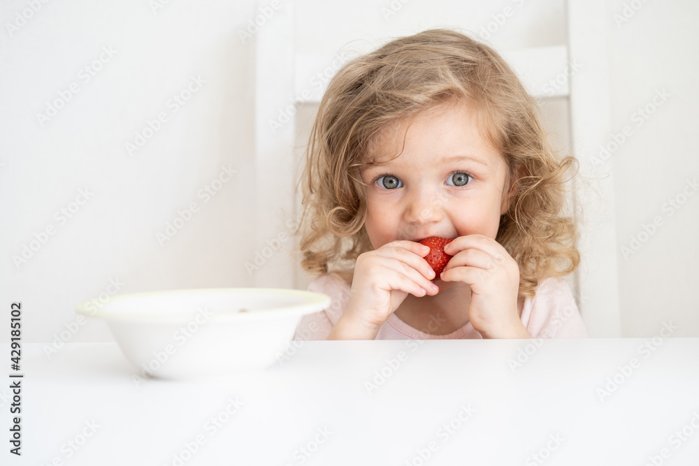 Curly beautiful baby girl eating apple on light gray background Curly beautiful baby girl eating apple on light gray background
