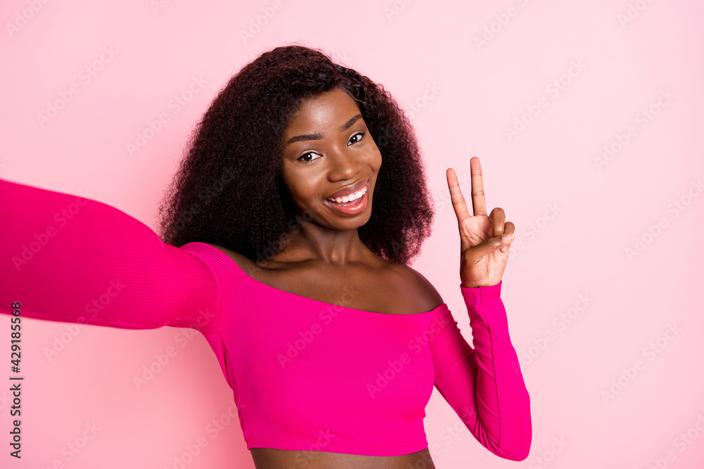Photo of african girl make selfie show v-sign wear top uncovered shoulders isolated pink color background