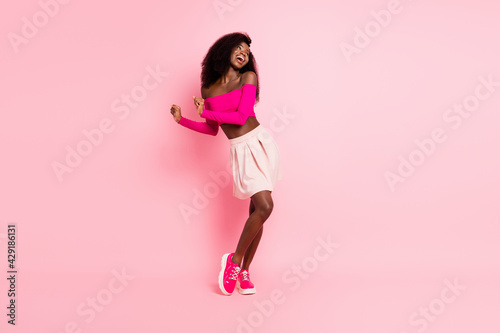 Photo of lady dance look empty space wear top uncovered shoulders mini skirt sneakers isolated pink color background