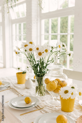 Beautifully served spring summer white table with lots of lemons and chamomile.