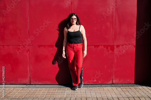 young curvy model with glasses and a red background