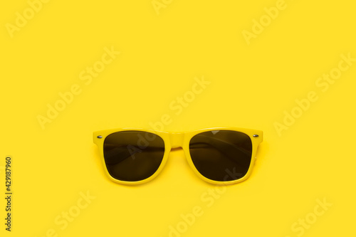 Gafas amarillas para el sol sobre un fondo amarillo liso y aislado. Vista superior. Copy space