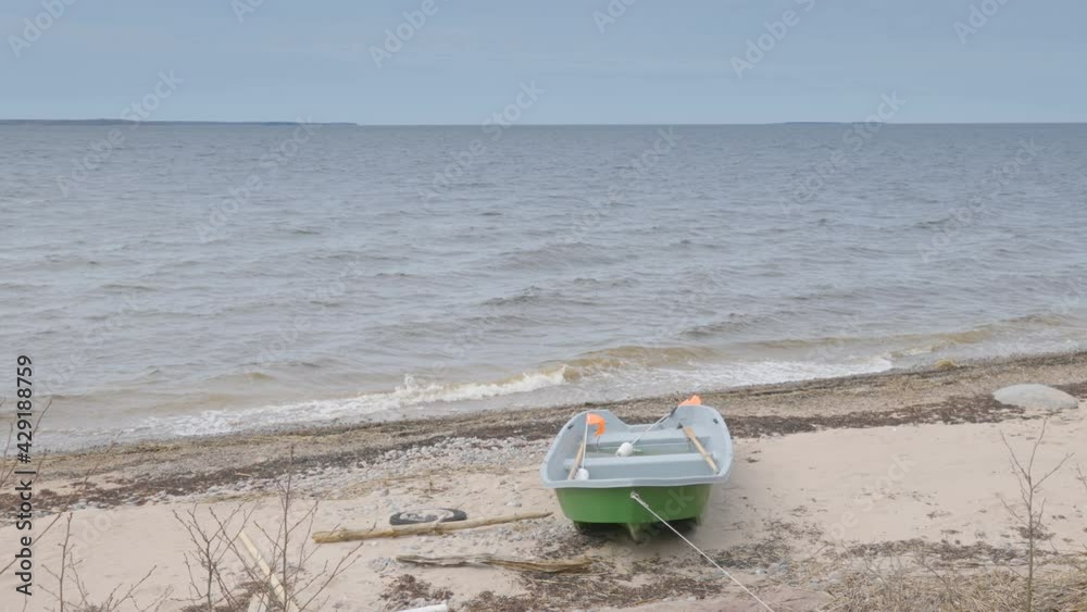A landscape view of the beach on a windy day with the green boat on the shoreline A landscape view of the beach on a windy day with the green boat on the shoreline
