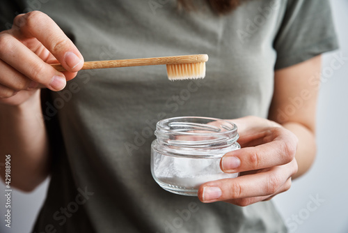 Woman holds bamboo toothbrush and soda powder in her hands