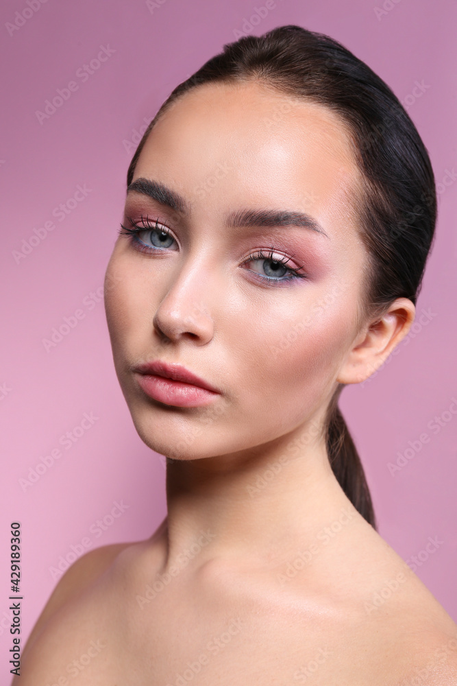 Fototapeta premium Portrait of young beautiful woman with perfectly clean face skin wearing professional make up. Female with long black hair tied in a ponytail. Close up, copy space background.