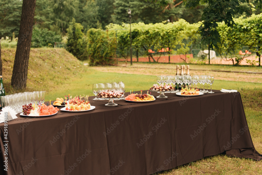 Large buffet table with a variety of snacks and champagne in nature