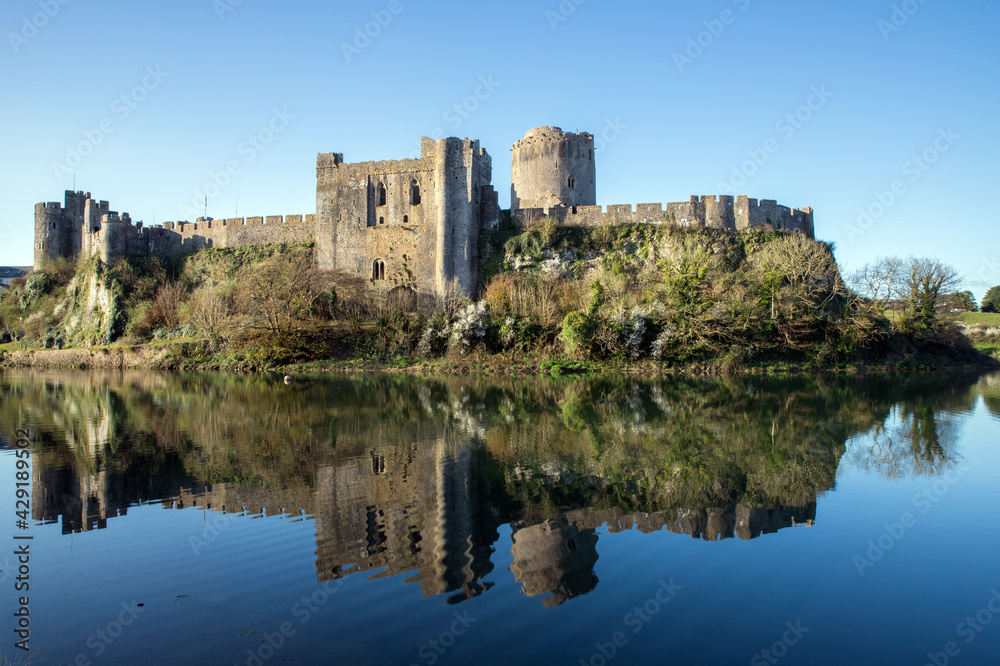 View of Pembroke castle in Pembrokeshire, Wales, UK with reflections on the water of the moat