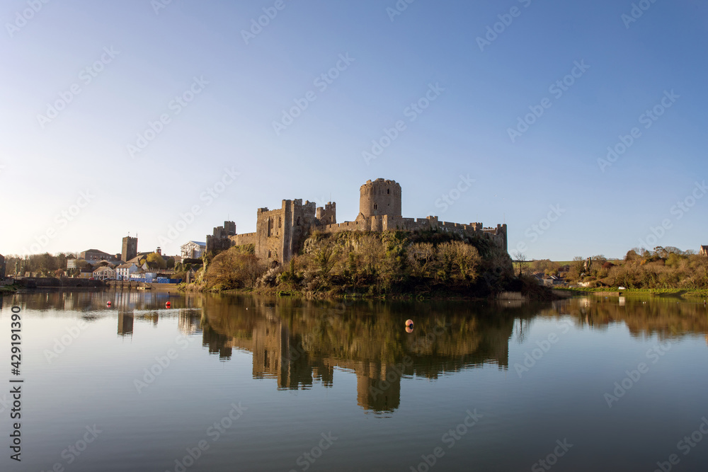 View of Pembroke castle in Pembrokeshire, Wales, UK with reflections on the water of the moat