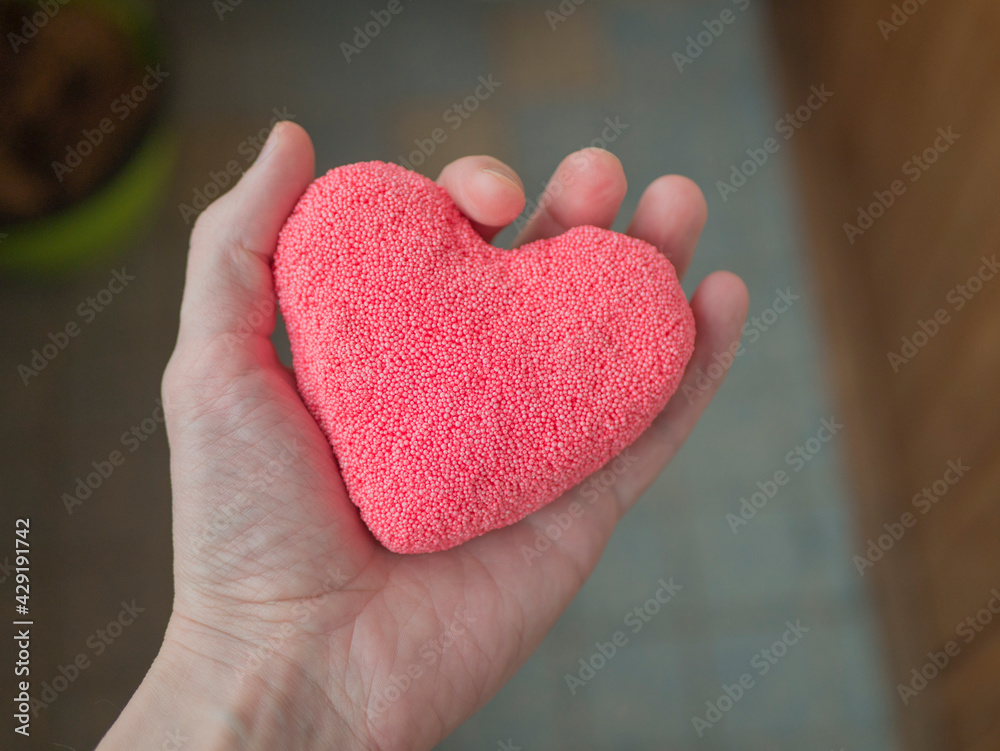 A man's hand holds a plasticine heart