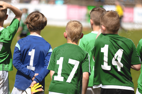 Boys in Green Soccer Jersey Shirts Standing in a Team and Watching Football Tournament Match. Kids Playing Sports Outdoor in Summer Sunny Day