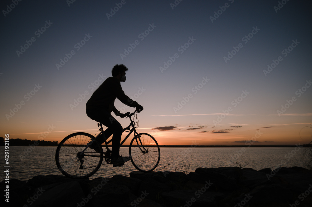 Hombre monta en bici al atardecer - obrazy, fototapety, plakaty 