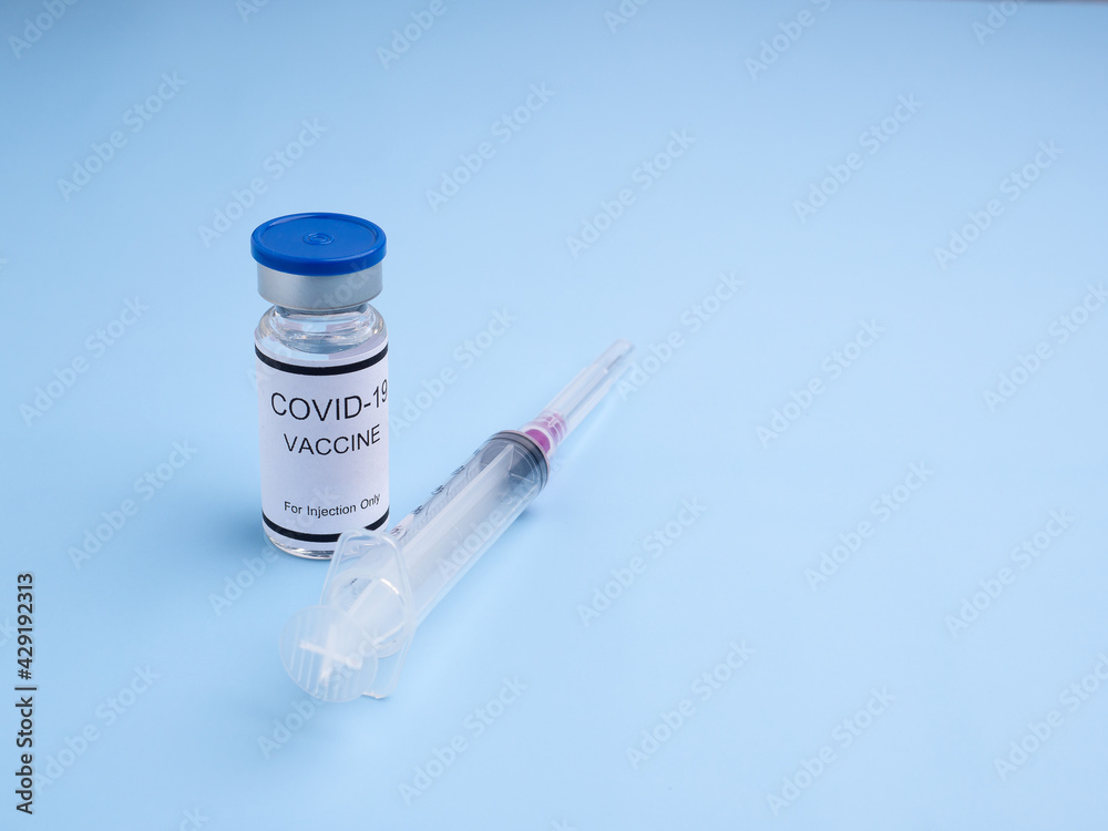 COVID-19 vaccine in glass bottle with a syringe placed on a light blue background. Vaccine for immunization, and treatment from coronavirus infection. Top view. Concept of medical and healthcare