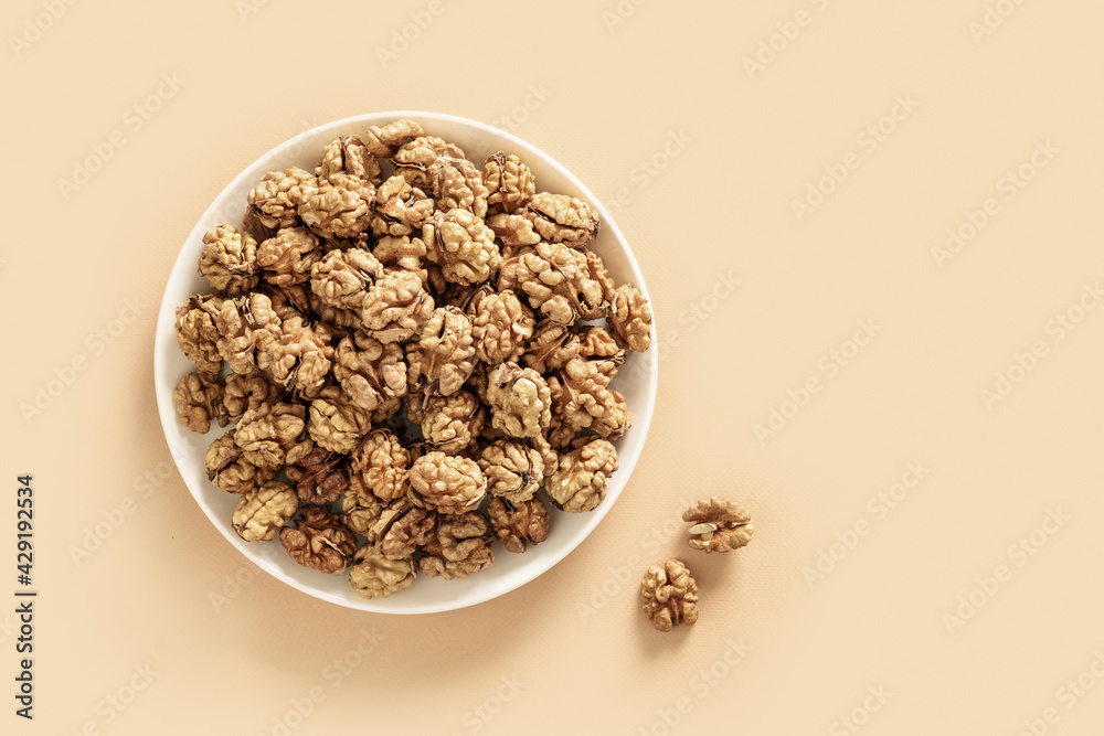 Healthy walnuts without shells in white plate on beige background with copy space. View from above. Healthy walnuts without shells in white plate on beige background with copy space. View from above.