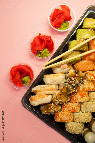 Asian food - set of rolls on a pink background in dishes for delivery. High quality photo