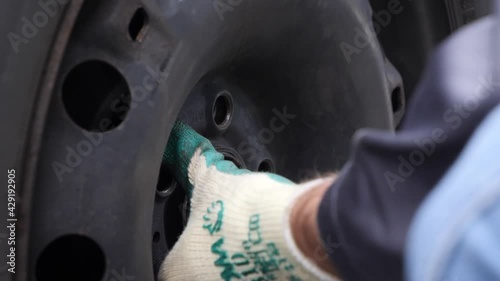 Extreme close up, mechanic unscrews a winter tire with an electric impact wrench photo