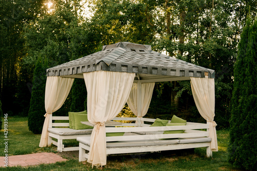 Fotografija Summer gazebo terrace with outdoor sofas made of white wood, roof and curtains
