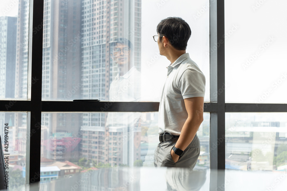 Businessman standing in office building looking through window. Businessman standing in office building looking through window.