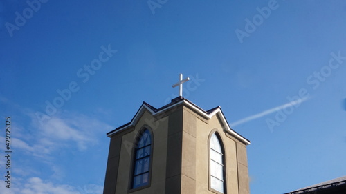 Stucco Church Tower with Cross against Blue Sky