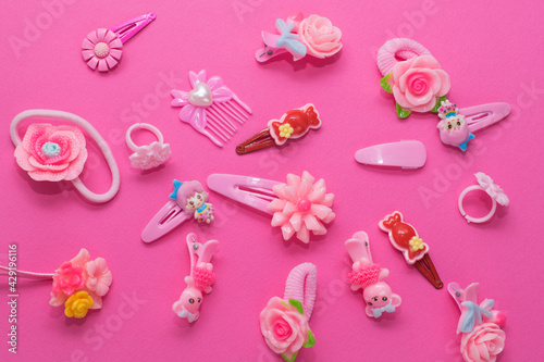 Children's flat lay, accessories for girls on a pink background, elastic bands, hair clips, children's rings.