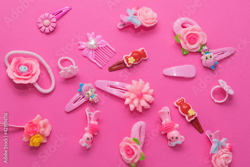 Fotografi Children's flat lay, accessories for girls on a pink background, elastic bands, hair clips, children's rings