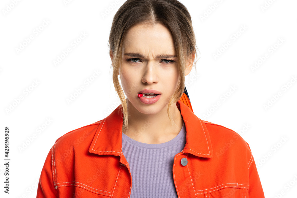 young woman with capsule in mouth looking at camera isolated on white