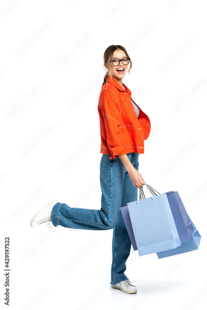 full length of happy woman in orange shirt holding shopping bags isolated on white full length of happy woman in orange shirt holding shopping bags isolated on white