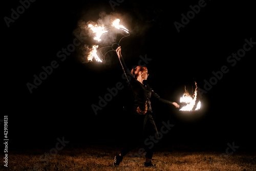 Fire show. Fakir juggles with fire Poi. Night performance. Illusion of a suspended object