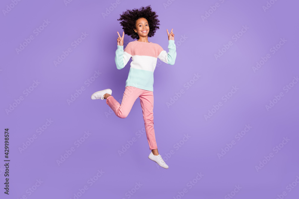 Full size photo of young beautiful pretty smiling cheerful afro girl jumping show v-sign isolated on purple color background