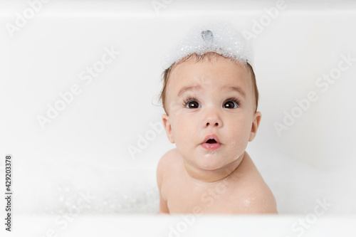 Cute baby girl in bubble bath with shampoo on head