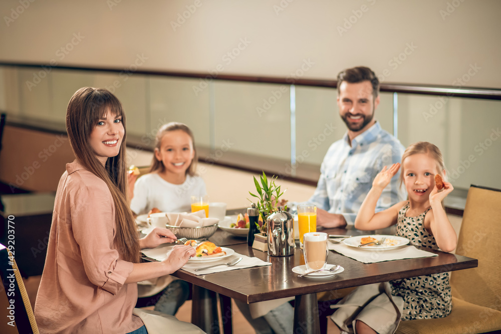 Smiling family sitting at the table and looking happy Smiling family sitting at the table and looking happy