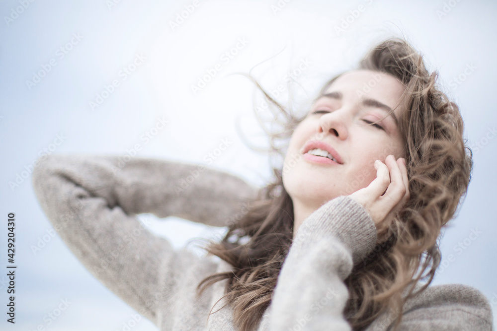 portrait of a beautiful sensual young woman, hair develops the wind, brunette with emotions, hands hair and face, seaside wind outside portrait of a beautiful sensual young woman, hair develops the wind, brunette with emotions, hands hair and face, seaside wind outside