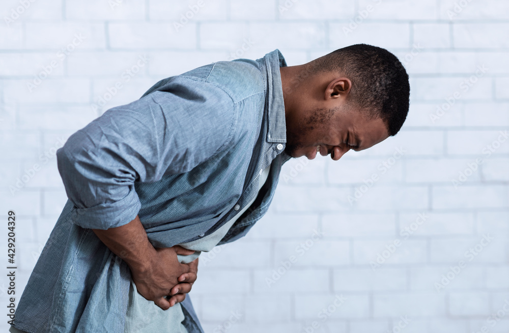 Obraz premium Black Man Suffering From Stomachache Standing Over White Wall, Side-View