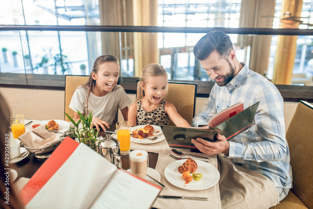 Cute family sitting at the table and cchoosing the meal Cute family sitting at the table and cchoosing the meal